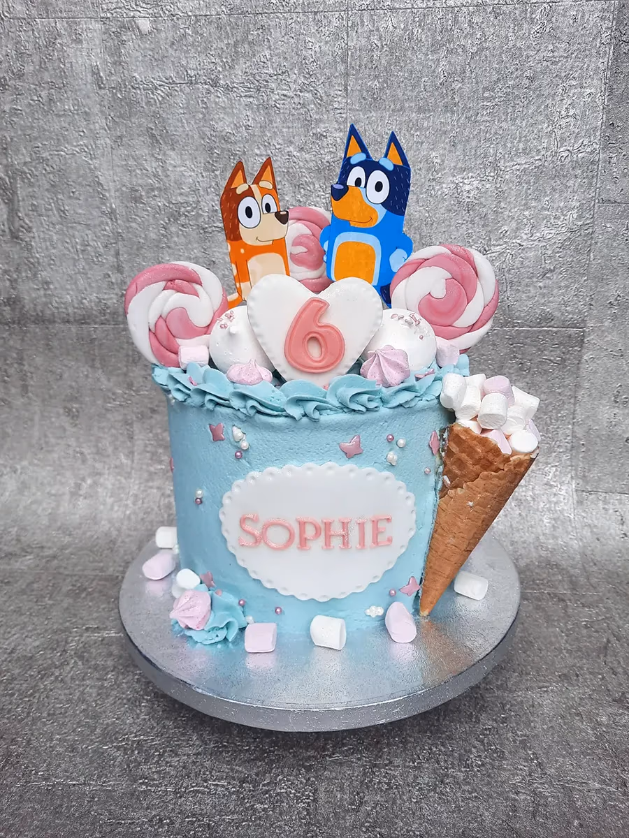 Bluey themed 6th birthday cake with blue lollipops and marshmallows
