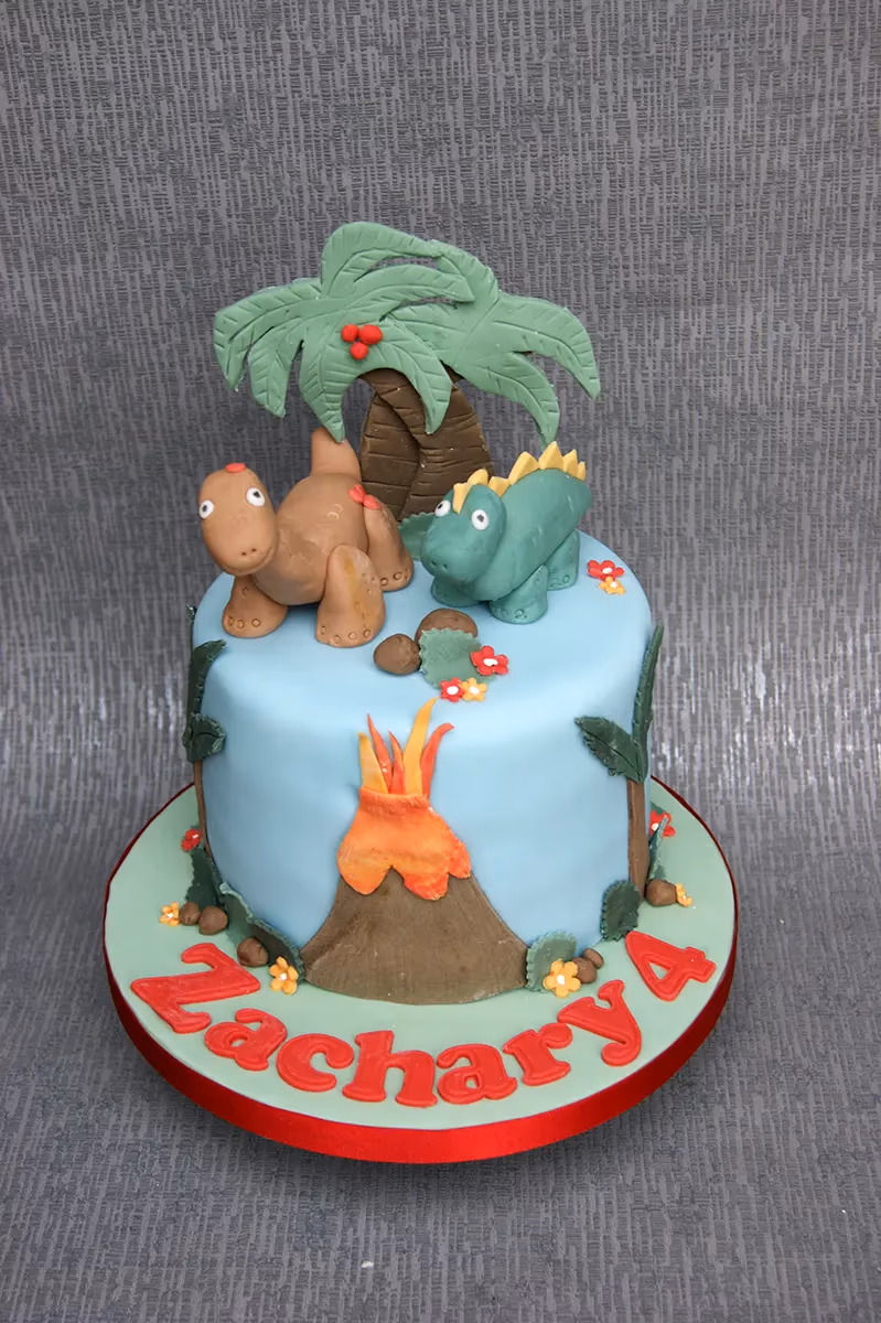 Dinosaur themed 4th birthday cake with a volcano and palm tree