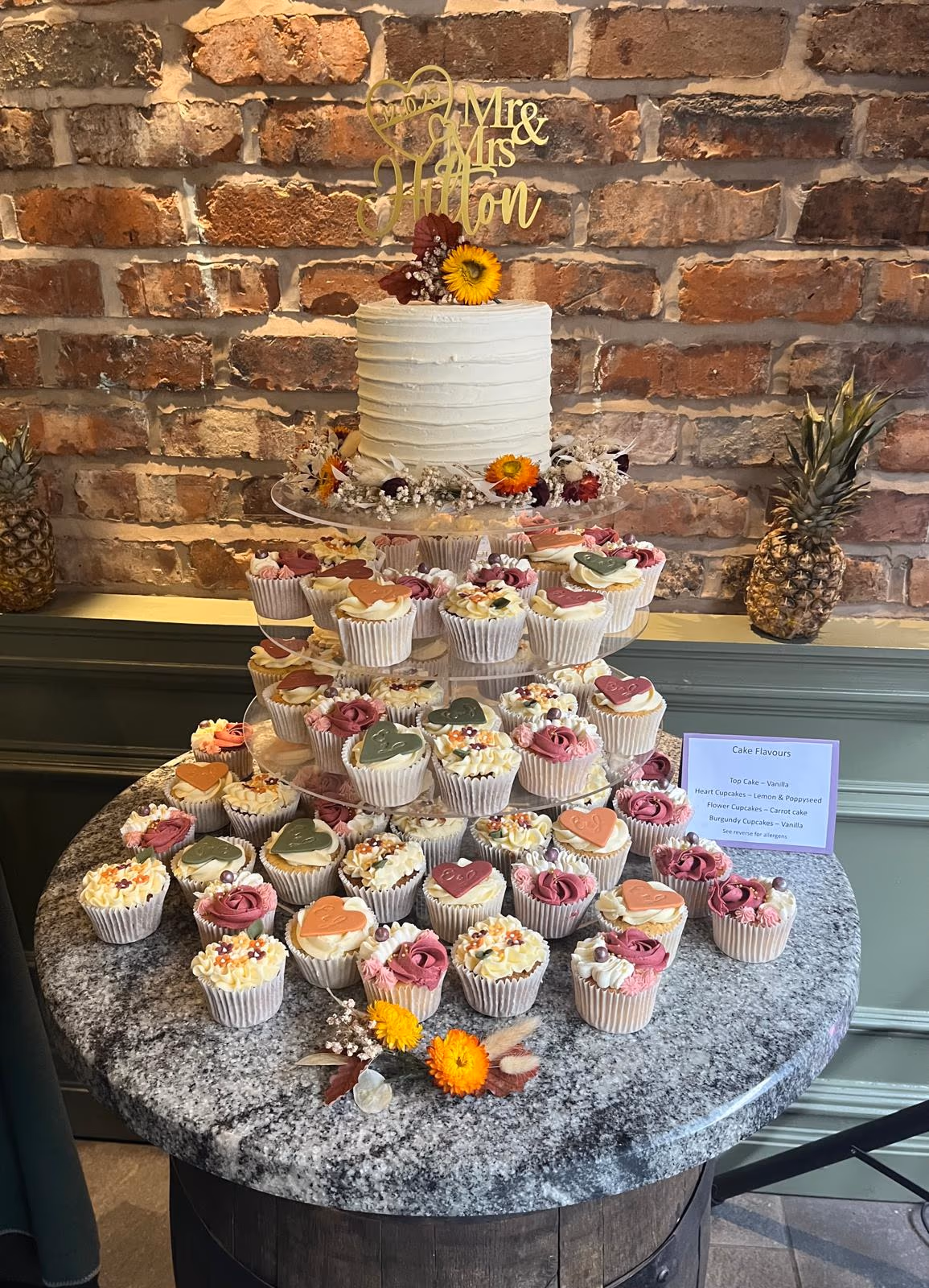 Autumn-themed wedding cupcake tower in pink, burgundy and orange beneath a single-tier wedding cake